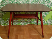 Litet soffbord med
                          brun perstorpsskiva, snedställda ben och
                          tidningshylla